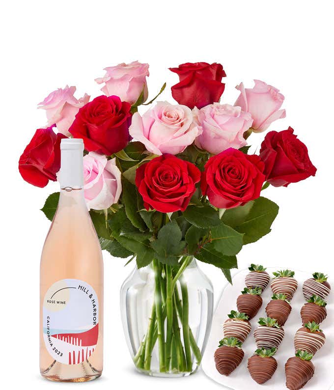 A mixed bouquet of 1 dozen red and blush roses in a clear vase is paired with a bottle of Hill & Harbor Rosé and 12 chocolate-covered strawberries.